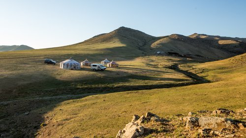 Mobile ger camp pitched on a green hillside above an empty valley