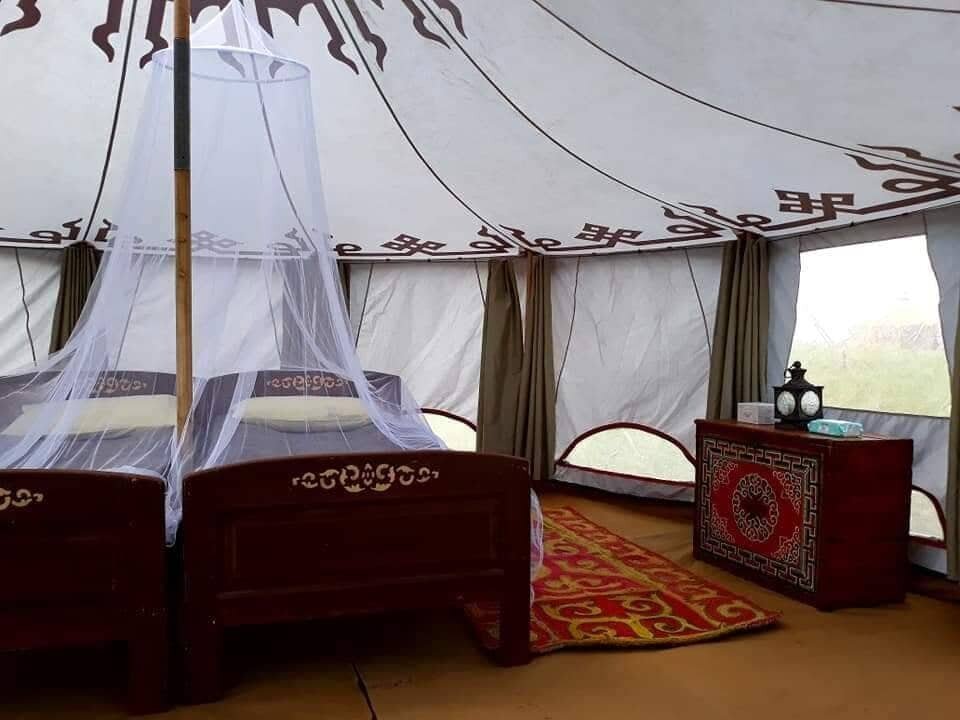 Inside a private mobile ger with twin beds under white mosquito nets and painted Mongolian furniture